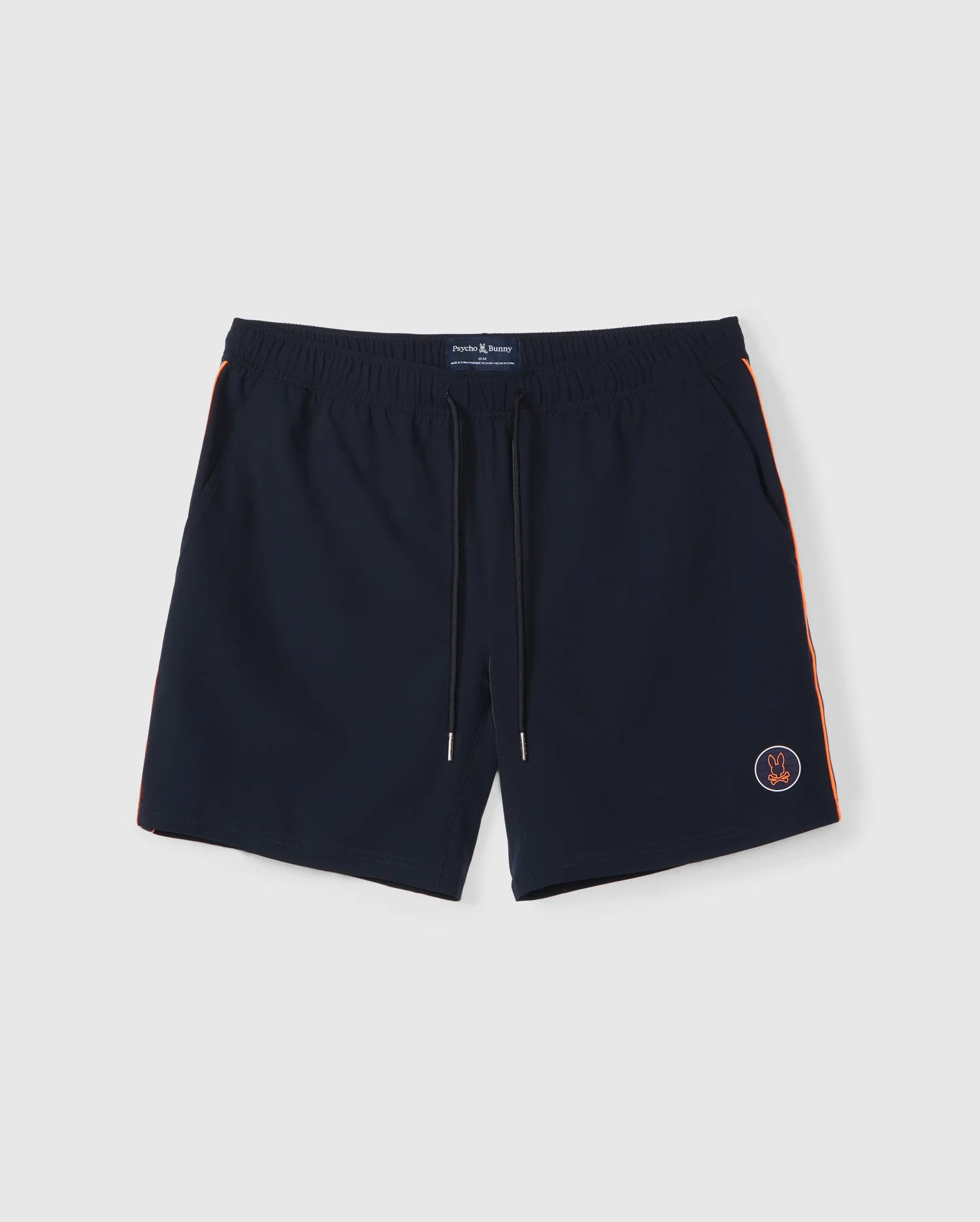 A pair of dark blue Psycho Bunny MENS SONTERRA STRIPE SPORT SHORT - B6R464C200 with an elastic waistband and drawstring, crafted from quick-drying stretch fabric. The shorts feature orange stripes along the sides and a small embroidered emblem near the bottom left hem, set against a plain white surface.