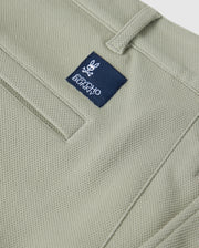 Close-up of a green Psycho Bunny honeycomb fabric material featuring a stitched pocket detailing and a small blue label with the logo "Psycho Bunny" on the upper part of the pocket.