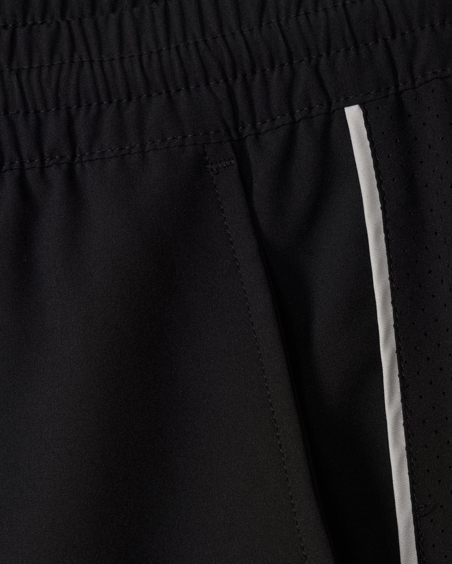 Here is a revised version of the sentence using the given product data:
A close-up of Psycho Bunny's MENS MANSFIELD SPORT SHORT - B6R807D200 in black, showcases an elastic waistband, side pocket, and a white stripe along the side. Made from polyester for a textured yet smooth look, these shorts provide a regular fit ideal for any active lifestyle.