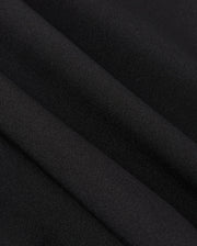 Close-up of smooth, black polyester fabric with visible folds, creating soft shadows and a subtle texture reminiscent of the MENS MANSFIELD SPORT SHORT - B6R807D200 by Psycho Bunny.