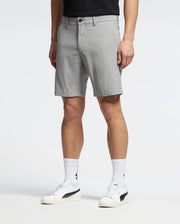 A person in Psycho Bunny's light gray MENS 10K STEP SHORT - B6R969F200 stands against a plain background, with white socks featuring black logos and white sneakers with black accents. Their upper clothing is black but mostly out of frame.