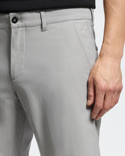Close-up of a person wearing MENS 10K STEP SHORT - B6R969F200 by Psycho Bunny, with a subtle rabbit logo on light gray fabric. They pair it with a black top, right hand on their thigh, highlighting the shorts' fit and breathable texture for ultimate athletic comfort.
