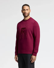 A man in a Psycho Bunny MENS OAK CITY CREW NECK - B6S274E200 stands against a plain white background. Sporting short hair and a beard, he looks directly at the camera while pairing his premium quality top with black pants.
