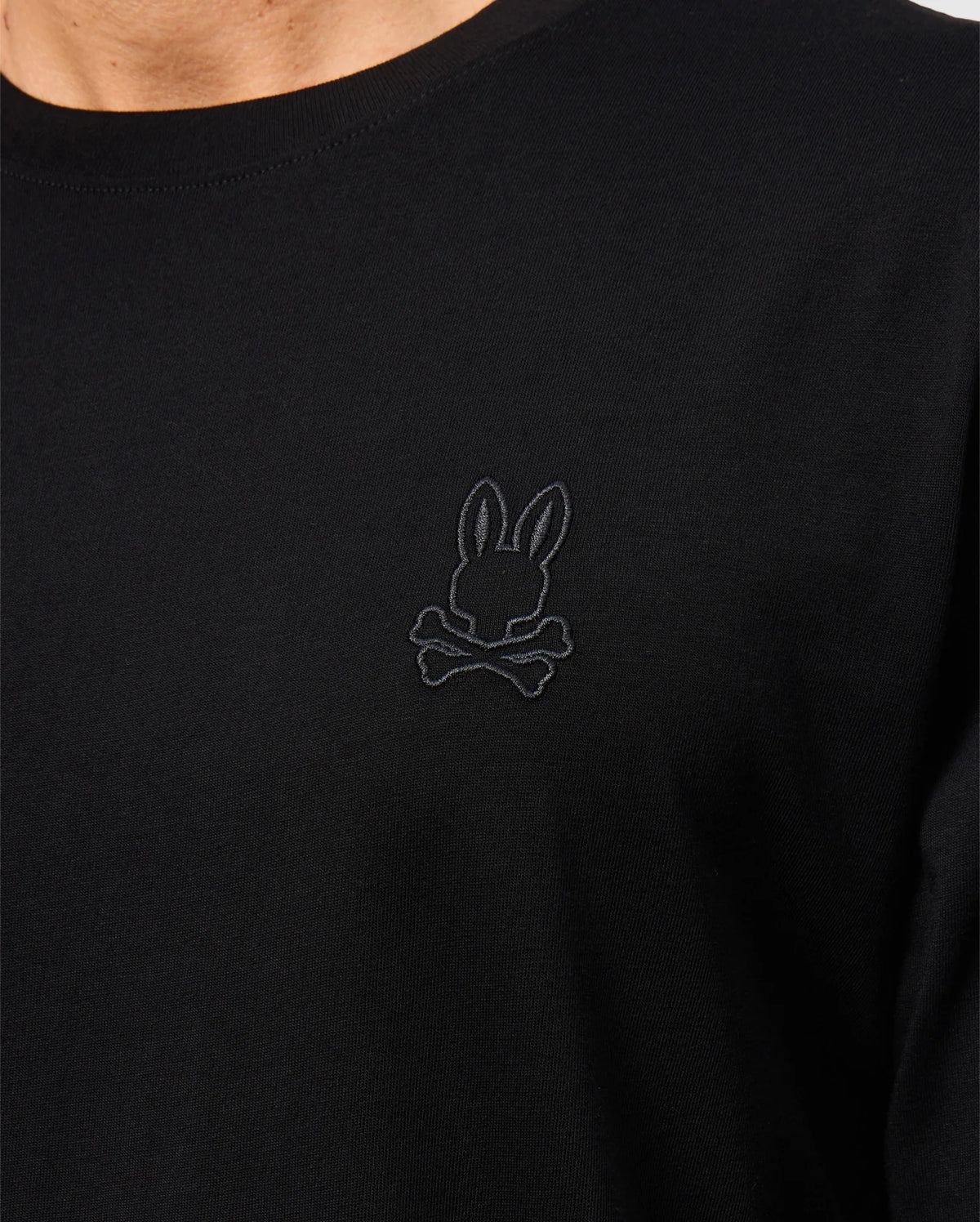 Close-up of the Psycho Bunny MENS ALBERTON LONG SLEEVE TEE - B6T867D200 in black, a true fashion masterpiece made from fine Pima cotton. It features an intricate dark embroidered design of a bunny head with crossed bones below it on the left side of the chest.