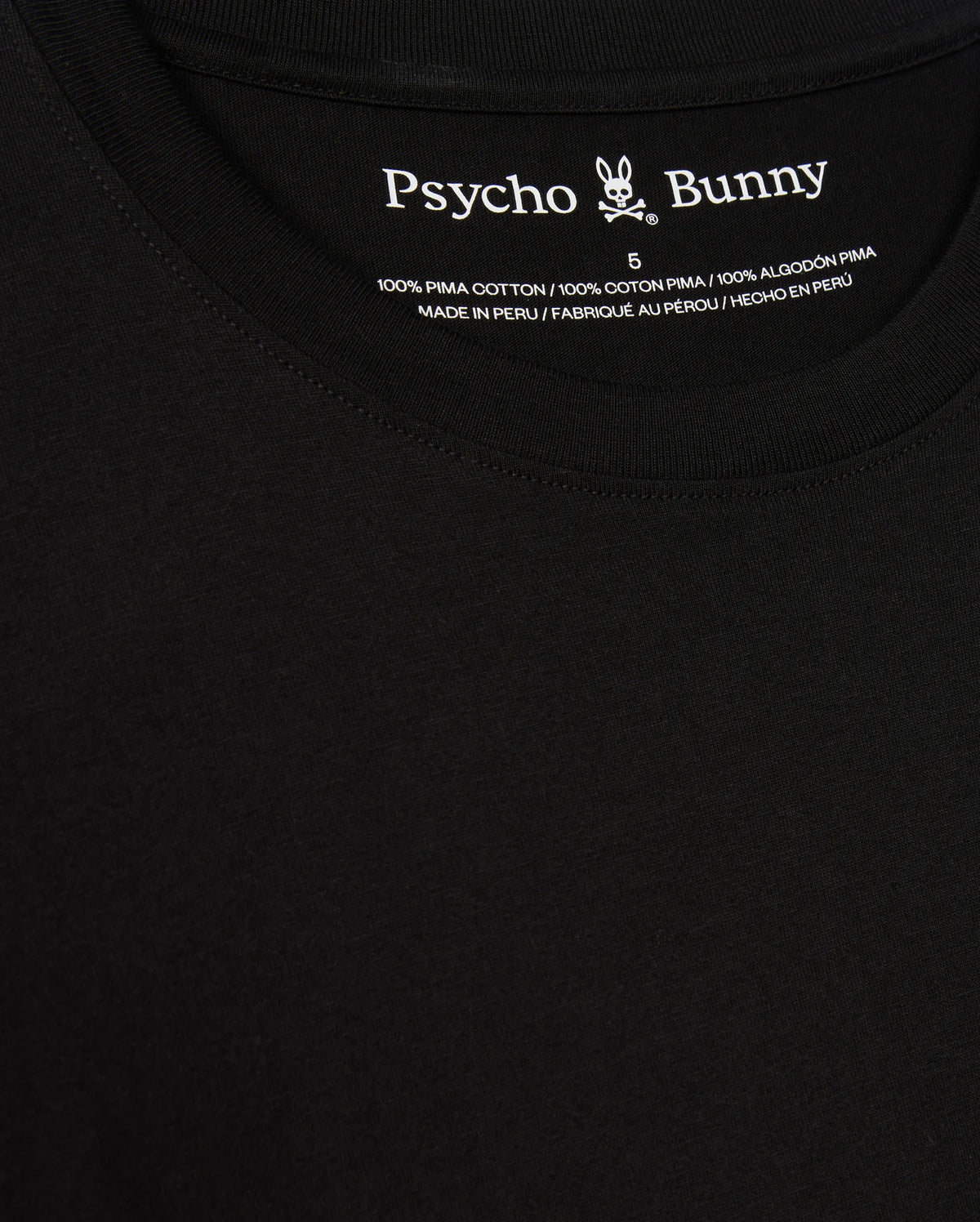 A close-up of the black Psycho Bunny Men's Alberton Long Sleeve Tee – B6T867D200 highlights its label. This fashion masterpiece features the "Psycho Bunny" name alongside a bunny logo and is detailed in white text: "100% Pima Cotton," "Made in Peru," and size "5".