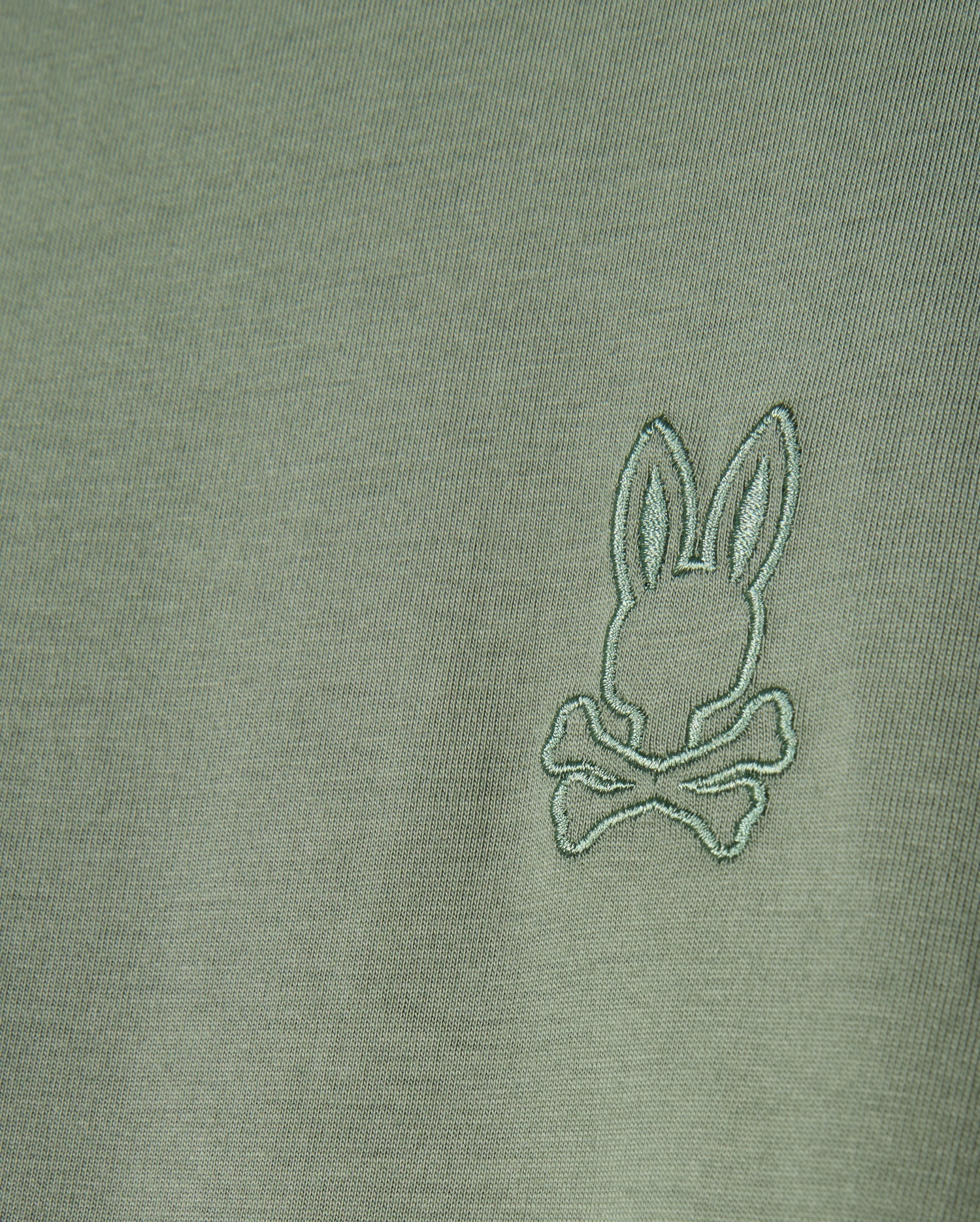 The MENS ALBERTON LONG SLEEVE TEE - B6T867D200 by Psycho Bunny is a fashion masterpiece, crafted from olive green Pima cotton and featuring an embroidered logo with a stylized rabbit head above crossed bones.