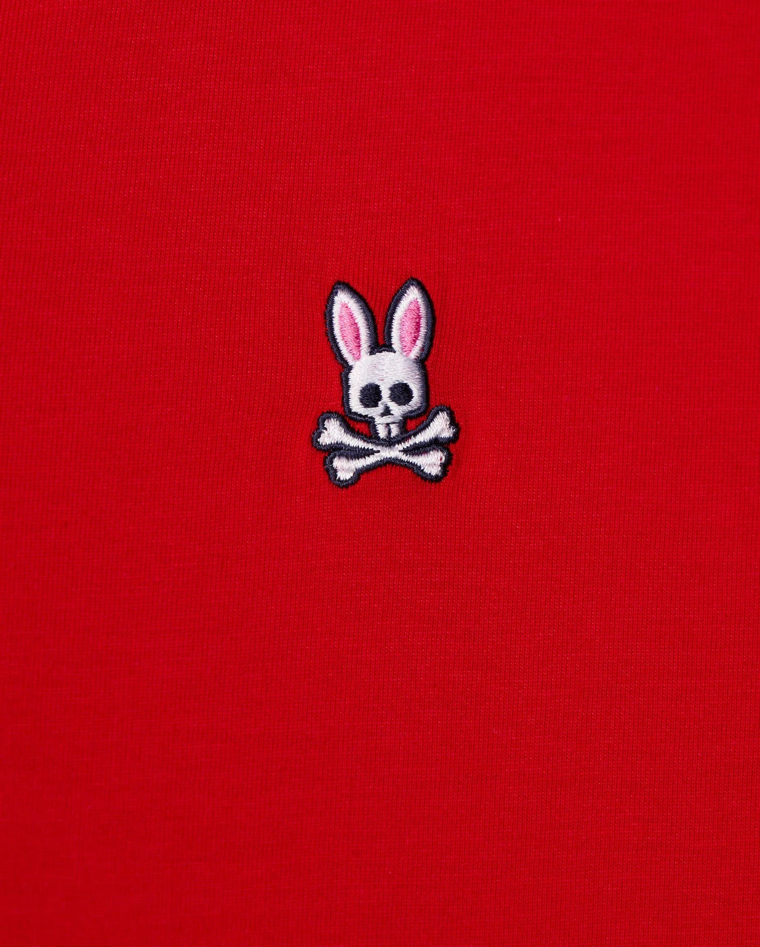 The MENS CLASSIC V NECK TEE - B6U100CRPC from Psycho Bunny showcases a red fabric made of soft Pima cotton and features the brand's signature logo: a white skull and crossbones with playful pink bunny ears.