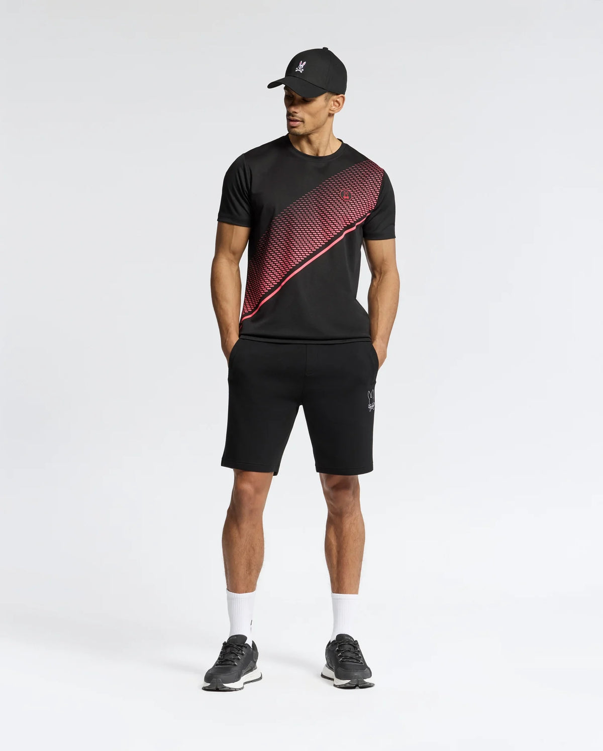 A man wearing a Psycho Bunny MENS MACK SPORT TEE - B6U335E200, made from premium Peruvian quality fabric, boasts moisture-wicking and quick-dry features for superior comfort.