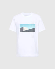 The Psycho Bunny MENS NEIL PHOTO REAL TEE - B6U389E200 is a white tee made from soft Peruvian Pima cotton, featuring an abstract rectangular design with a pale green cactus silhouette and a gradient blue-to-beige background, accented by artfully placed small text lines.
