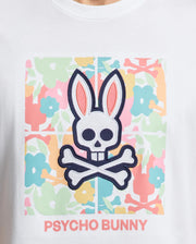 The Psycho Bunny MENS LEMORA GRAPHIC TEE (B6U657F200) in Pima cotton features a skull and crossbones graphic shaped like a bunny’s head with large ears, adorned with pastel pink, blue, and green flowers. "PSYCHO BUNNY" is boldly printed beneath this water-based masterpiece.