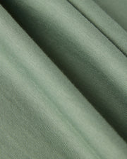 Close-up view of a smooth, green fabric with a subtle texture, characteristic of luxurious Pima cotton. The folds create gentle shadows, emphasizing the material's soft and slightly ribbed surface—ideal for crafting the high-quality MENS MALTON GRAPHIC TEE - B6U795D200 by Psycho Bunny.