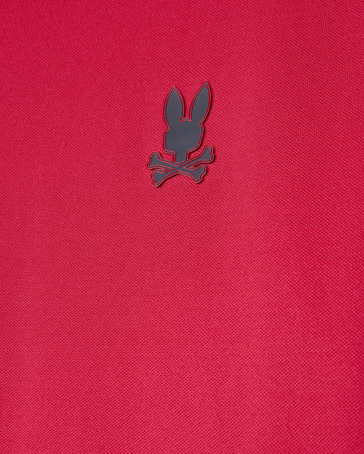 The Psycho Bunny Mens Edmonds Sport Tee (B6U857D200) is a red, textured shirt made from quick-drying, antimicrobial fabric with a small, dark emblem of a rabbit head and crossbones.