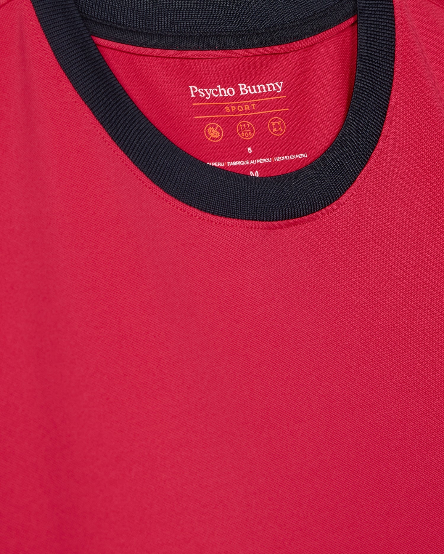 The Psycho Bunny Men's Edmonds Sport Tee (B6U857D200) features a red design with a black collar, crafted from quick-drying antimicrobial fabric. The brand name and care instructions are printed inside near the neckline.