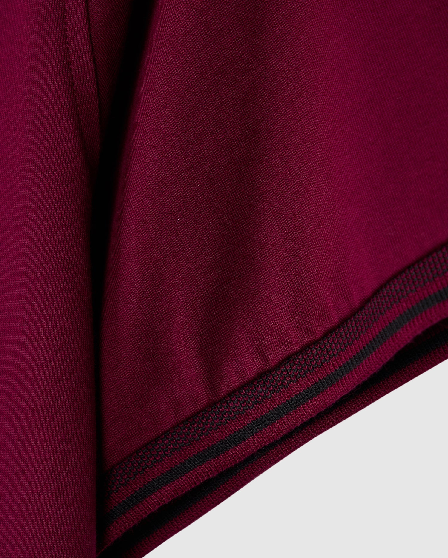 A close-up of the maroon fabric with black and green stripes mirrors the stylish design of the MENS MALTON FASHION TEE - B6U966D200 by Psycho Bunny. The thick, slightly textured material fits perfectly within men's fashion tees. Narrow stripes run parallel to the edge, adding a sleek element reminiscent of pima cotton's elegance.