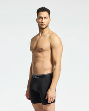 A man stands against a light gray background wearing the MENS SOLID KNIT 2 PACK BOXER BRIEF - B6V906ARCM by Psycho Bunny. He looks ahead with his arms at his sides, showcasing comfort and style in these ultrasoft modal-blend boxer briefs.