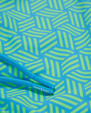 Blue jump rope with the text "MENS JASPER LIGHTWEIGHT SWIM TRUNK" on the handles, lying on a green and blue geometric-printed background.
