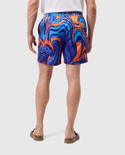 A person wearing a white shirt and vibrant MENS NEVADA ALL OVER PRINT SWIM TRUNK - B6W526C200 by Psycho Bunny with a blue, orange, and purple swirl print stands facing away. They are also wearing beige flip-flops. Their arms are relaxed by their sides, and the background is plain white. The swim trunks feature quick-dry fabric for added comfort.