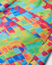 Close-up of a fabric showcasing the vibrant, multicolored pattern of the MENS DENNIS ALL OVER PRINT SWIM TRUNK - B6W530C200 by Psycho Bunny. The quick-dry material features shades of red, blue, green, and yellow, with an abstract and colorful design reminiscent of stylish swim trunks. A rectangular pocket with a flap is highlighted by detailed stitching in blue thread.
