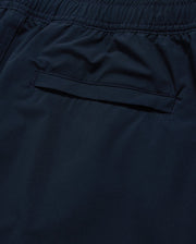Close-up of a dark blue Psycho Bunny MENS MELVIN SWIM TRUNK - B6W665C200, focusing on a stitched pocket with a concealed zipper. The smooth fabric features a quick-dry outer shell, and the waistband is gathered with elastic and complemented by a drawstring stretch for a comfortable fit. The neat stitching highlights attention to detail in the garment’s design.