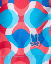The MENS WALTER LIGHTWEIGHT PRINT SWIM TRUNK - B6W863D200 from Psycho Bunny showcases a vibrant design with large, overlapping blue, white, and red circles. Crafted from 100% polyester, it features a unique detail in the lower right center: a small patch with a blue bunny skull and crossbones symbol.
