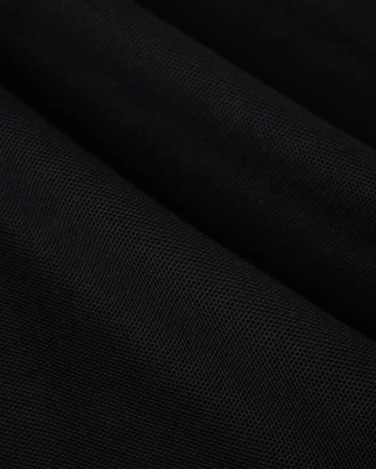 A close-up of black Pima cotton fabric drapes gracefully, showcasing soft, diagonal folds and shadows on this Psycho Bunny BIG AND TALL MALTON PIQUE POLO SHIRT - B9K950D200.
