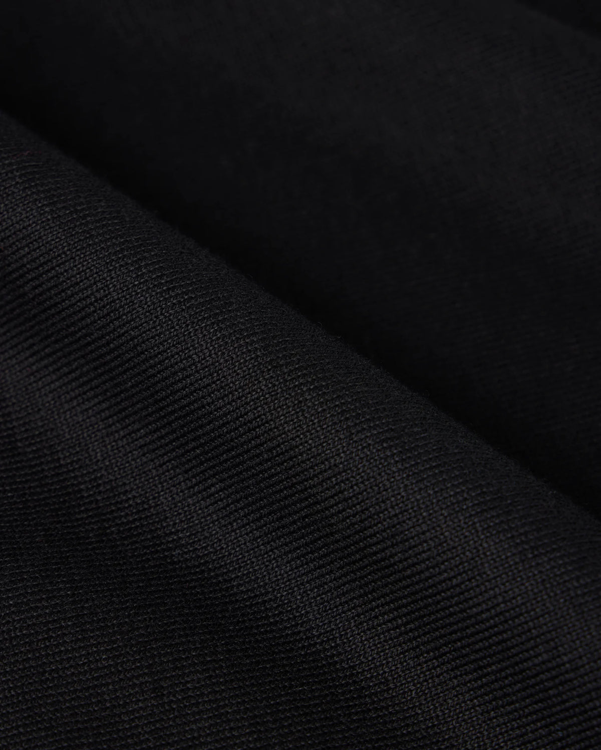 Close-up of a black heavyweight Pima cotton fabric with diagonal texture, subtle pattern, and smooth appearance. The image evokes elegance and simplicity, reminiscent of the relaxed-fit BIG AND TALL DUKE OVERSIZED TEE by Psycho Bunny.