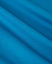 Close-up of the vibrant blue Pima cotton used in the Psycho Bunny BIG AND TALL MALTON GRAPHIC TEE - B9U795D200, featuring fine diagonal lines for a textured look. The soft fabric showcases Peruvian craftsmanship with gentle folds suggesting movement and fluidity.