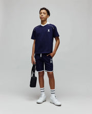 Navy blue polo with white collar and piping, featuring an embroidered bunny skull on the chest, and Kids Toby Short with white trim and a large Psycho Bunny text logo on the leg.