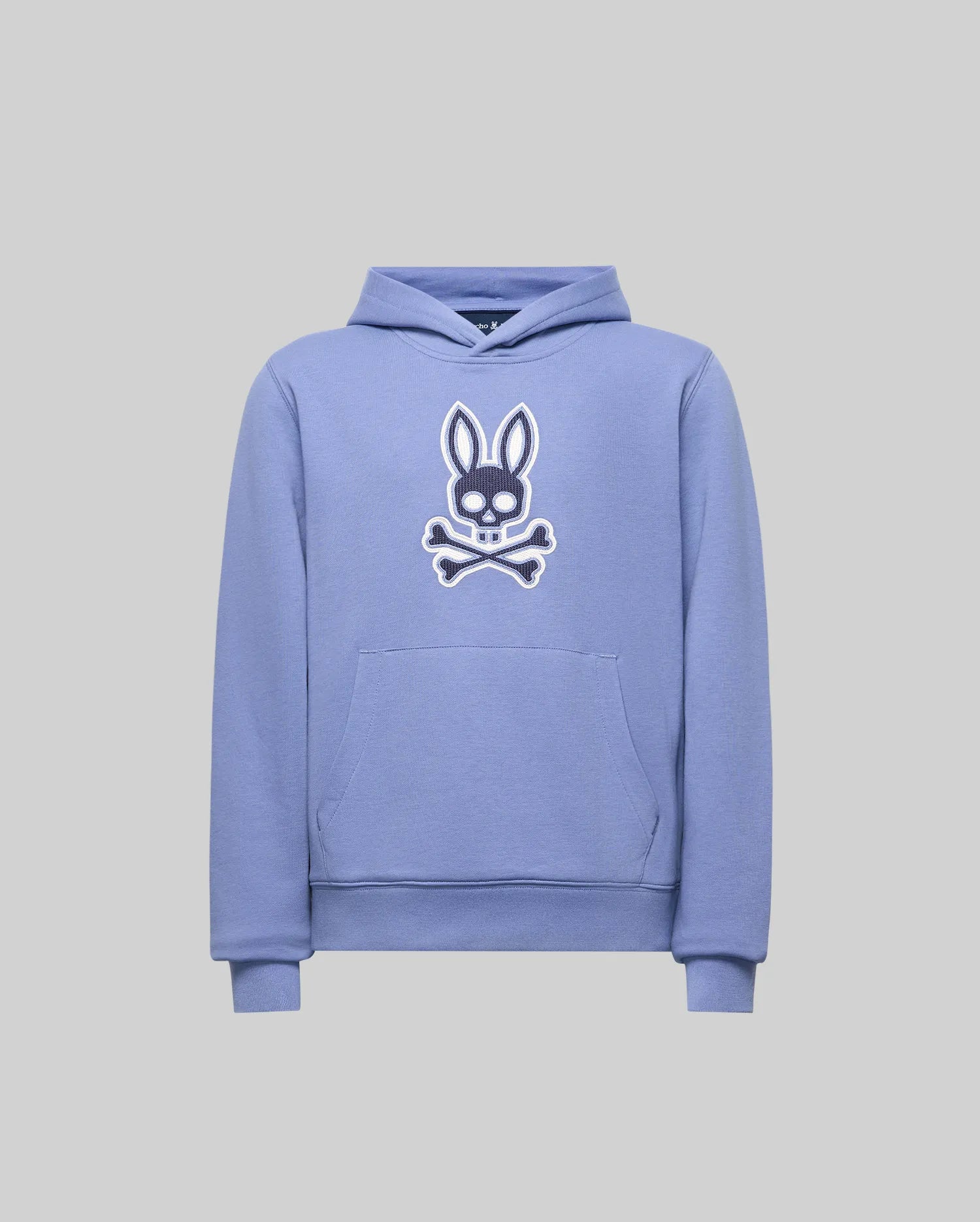 The KIDS RYDER BUNNY HOODIE - KT0500018 by Psycho Bunny is a light purple hoodie with a hood and front pocket, featuring a white embroidered bunny head and crossbones patch on the chest. Ideal loungewear in soft style.