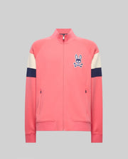 The Psycho Bunny MENS DAWSON TRACK JACKET (MT0500113) is a pink zip-up with cream and navy sleeve stripes, a blue bunny and crossbones logo on the left chest, made from a soft cotton-modal blend, shown on a plain gray background.