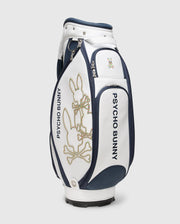 The OUTLINE BUNNY GOLF TOUR BAG - PBMG4FC1 by Psycho Bunny features the iconic "Psycho Bunny" branding in navy and white with a stylized bunny logo. This sleek polyurethane bag offers five-pocket club dividers and multiple compartments for optimal organization on the course.