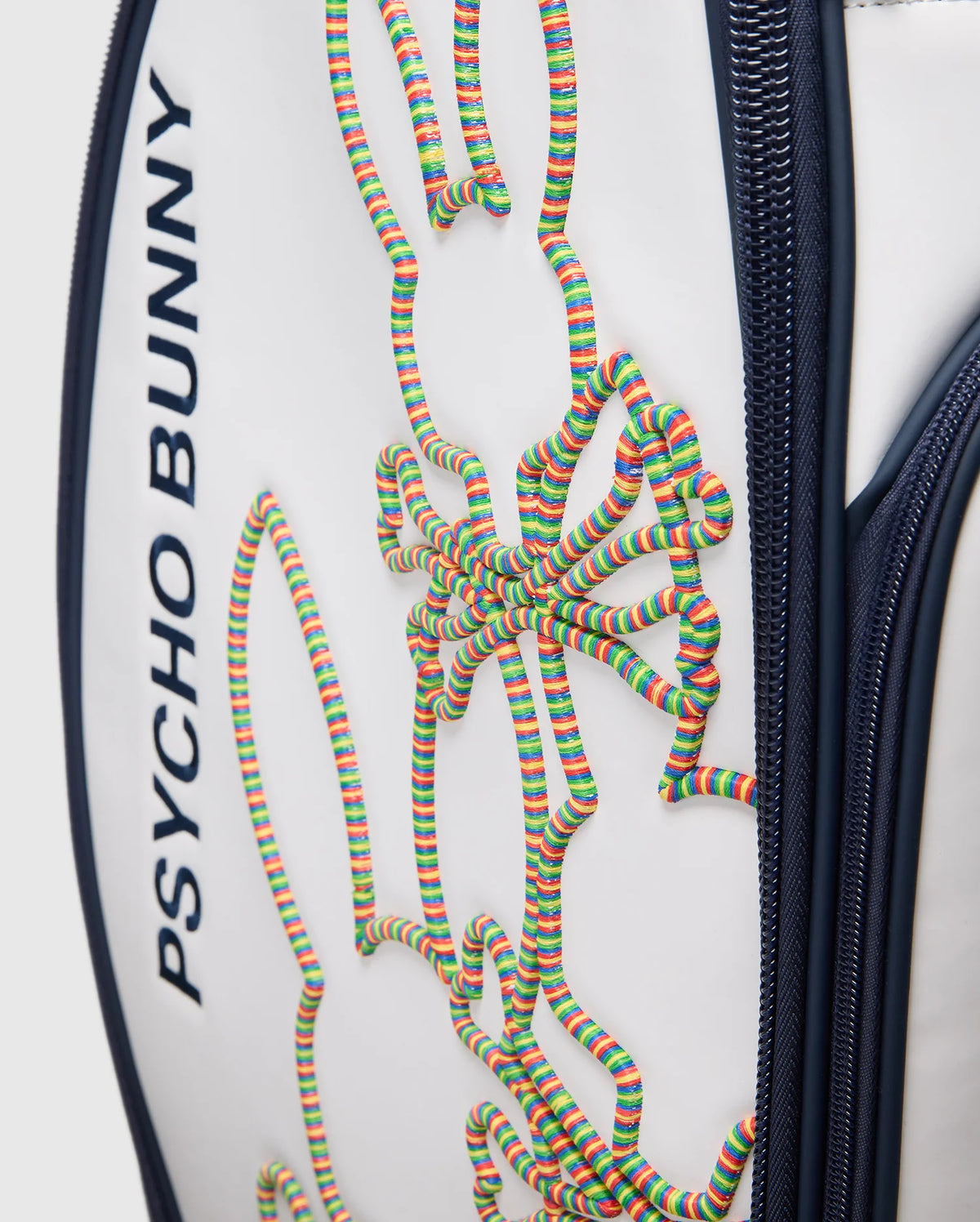 A close-up of the OUTLINE BUNNY GOLF TOUR BAG - PBMG4FC1 from Psycho Bunny shows its white polyurethane build with dark blue accents, a vibrant 3D bunny design in coiled strings, and features like zippers and five-pocket club dividers for easy organization on the course.