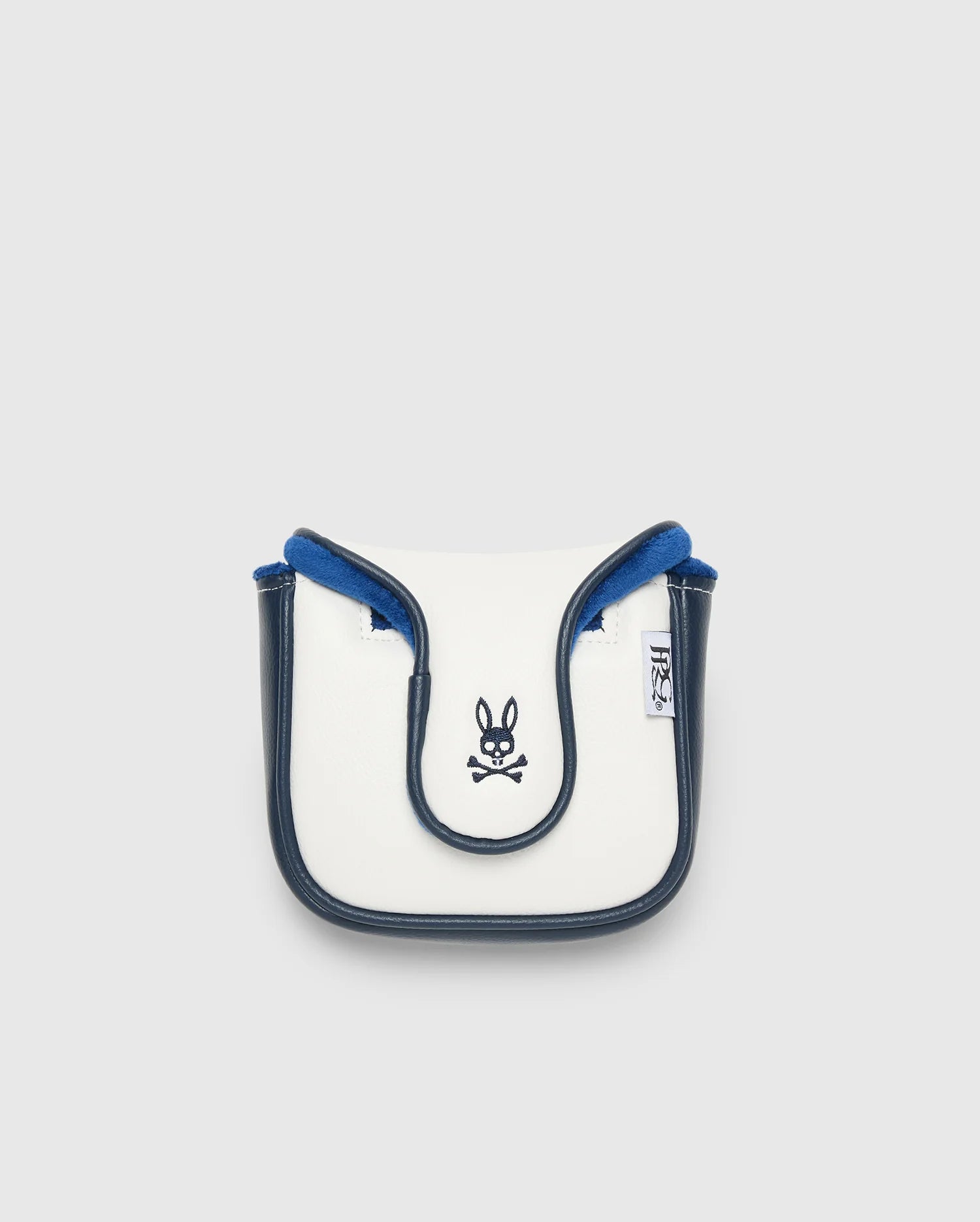 A small, white and blue crossbody bag with black trim, made from durable polyurethane. It showcases a Psycho Bunny logo with crossbones on the front and a side branded tag. Manufactured in China, it's displayed against a plain light background.