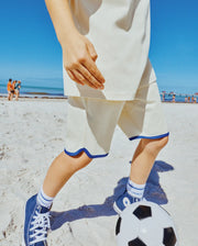 Psycho Bunny Kids Toby Short, cream relaxed-fit jersey shorts with a distinctive blue scalloped hem and contrast piping.