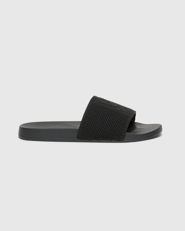 The Psycho Bunny KIDS KNIT SLIDES - B0A377F200 is a black slide sandal for kids, featuring a textured strap, flat sole, and molded footbed for comfort. It has a minimalist design without visible branding and is displayed on a plain white background.