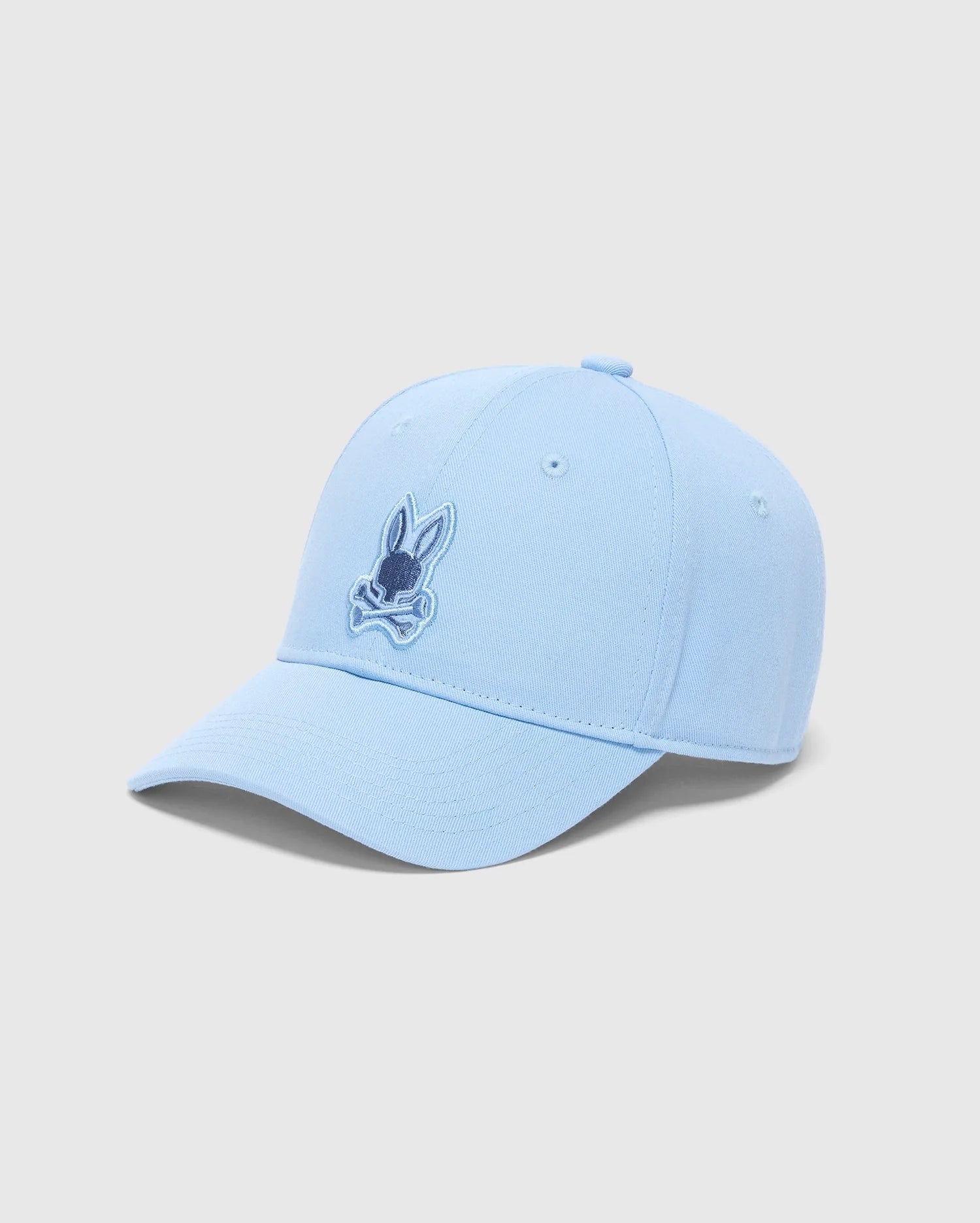 Light blue Psycho Bunny KIDS NEW CASTLE EMBROIDERED BASEBALL CAP (B0A547F200) with a stylized rabbit head and crossbones design, 100% cotton, curved brim, six panels, top button, ventilation eyelets, and adjustable strap.