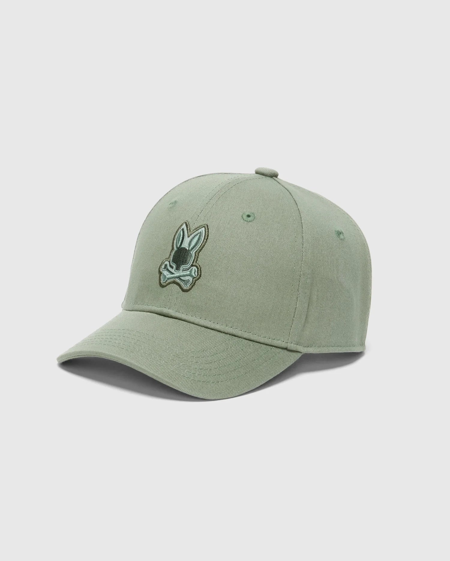 The Psycho Bunny KIDS NEW CASTLE BASEBALL CAP - B0A547F200 is a light green cotton twill cap with a dark green embroidered rabbit head logo wearing a bow tie. It features a curved brim and an adjustable back strap for the perfect fit.