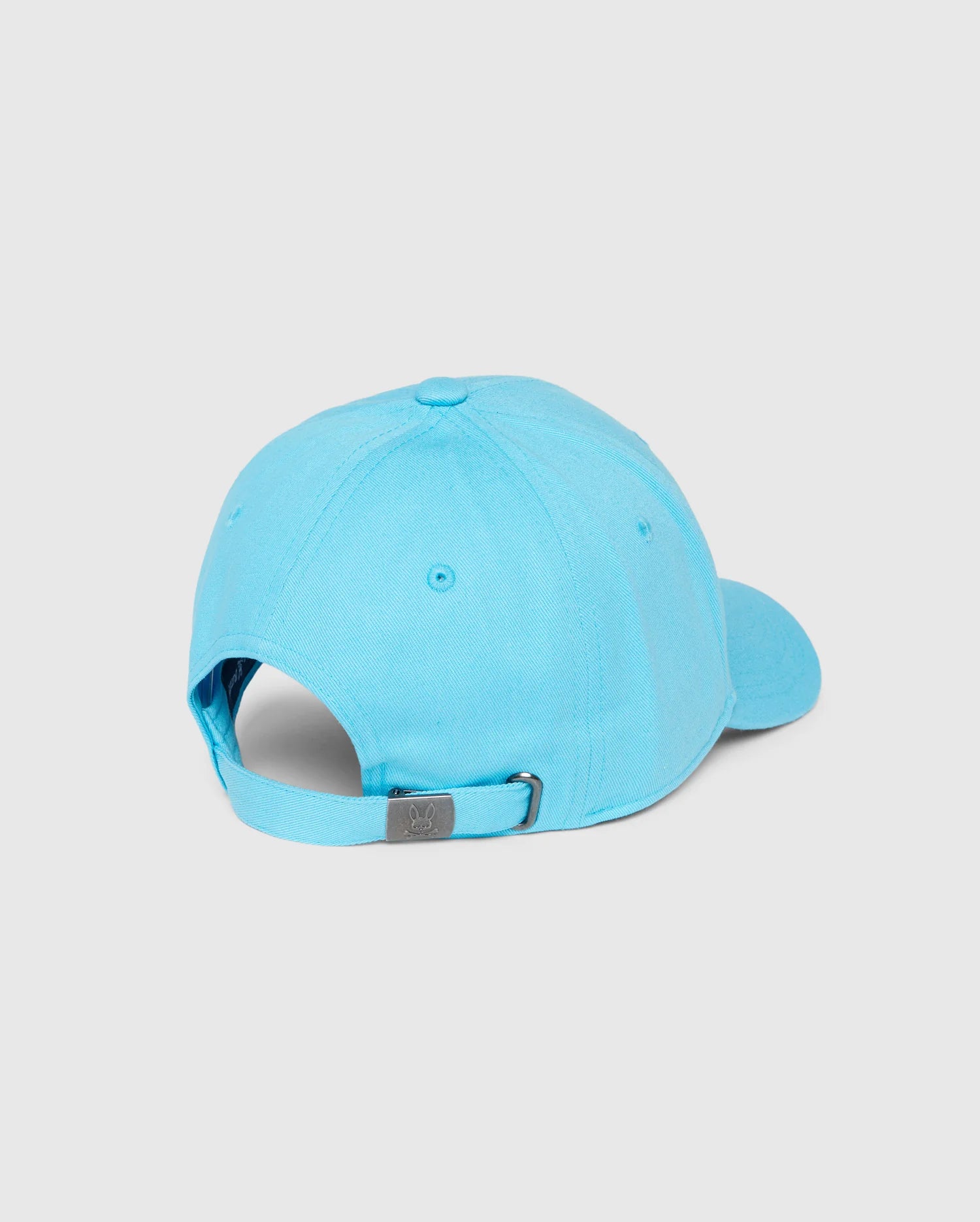 The Psycho Bunny KIDS LOUISE BASEBALL CAP - B0A551C200 is shown from the back, displaying its bright blue cotton twill, curved brim, and adjustable strap with a metal buckle against a plain light gray background, highlighting its simple elegance.