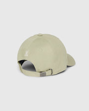 A light beige cotton twill baseball cap from Psycho Bunny, named the Kids Kayden Baseball Cap - B0A677C200, is viewed from the back. The cap features a metal buckle for size adjustment and an embroidered Bunny logo above the opening. The fabric has a smooth texture, and the cap is displayed against a plain, neutral background.