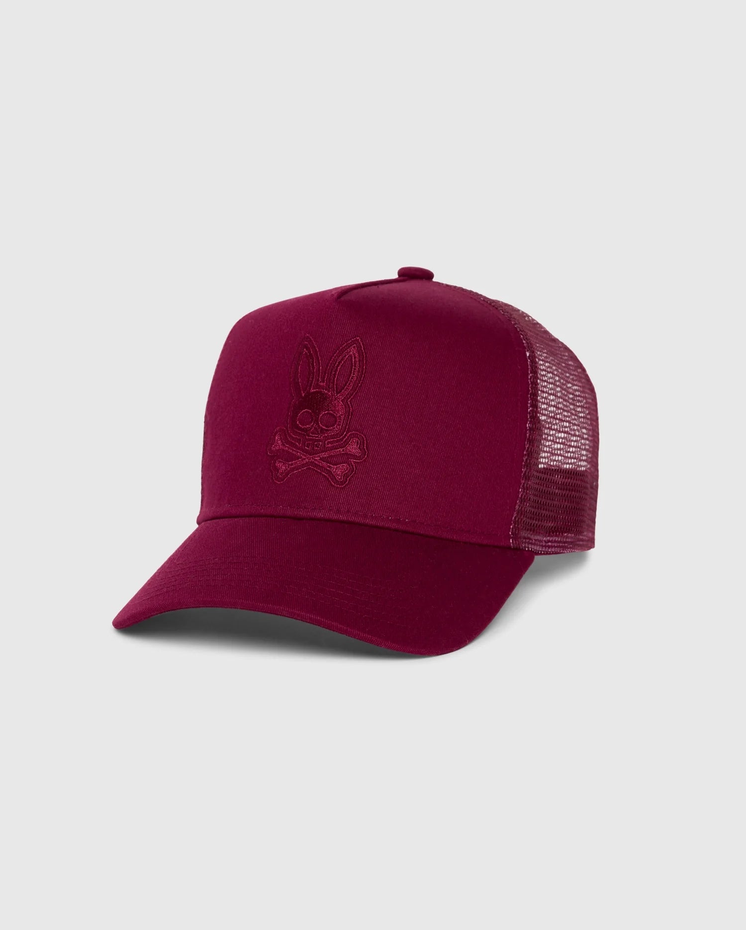 The KIDS MALTON TRUCKER CAP (B0A797D200) by Psycho Bunny is a maroon kids trucker cap with a mesh back, featuring an embroidered bunny skull and crossbones. Set against a plain gray background, its subtle design makes it an ideal accessory for an active lifestyle.