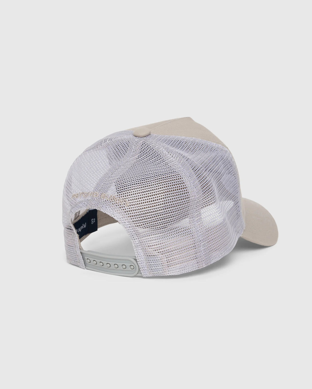 The back view of the KIDS MALTON TRUCKER CAP - B0A797D200 by Psycho Bunny showcases a beige and white design with a curved brim. The cap features a white mesh back for optimal ventilation and an adjustable snapback closure. Its front panel is solid and structured, made from cotton. The background is plain white.