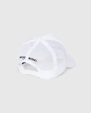 Viewed from the back, the Kids Bunny Patch Trucker Cap by Psycho Bunny features a white mesh with a solid brim. "Psycho Bunny" is embroidered in black on the mesh panel, complemented by a Bunny logo patch and an adjustable snapback closure.