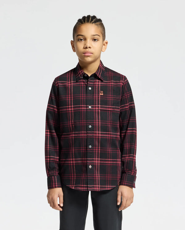 A person with braided hair wears a Psycho Bunny Kids Hayes Plaid Shirt - B0C842D200, showcasing black and red long sleeves, paired with black pants and standing against a plain white background.