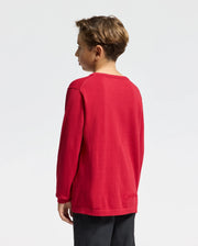 A young boy with short hair stands against a plain white background, looking to the side while wearing the Psycho Bunny KIDS COORY CHAINSTITCH COTTON SWEATER - B0E893E200. This long-sleeve red sweater is crafted from extra fine cotton for a gentle drape.