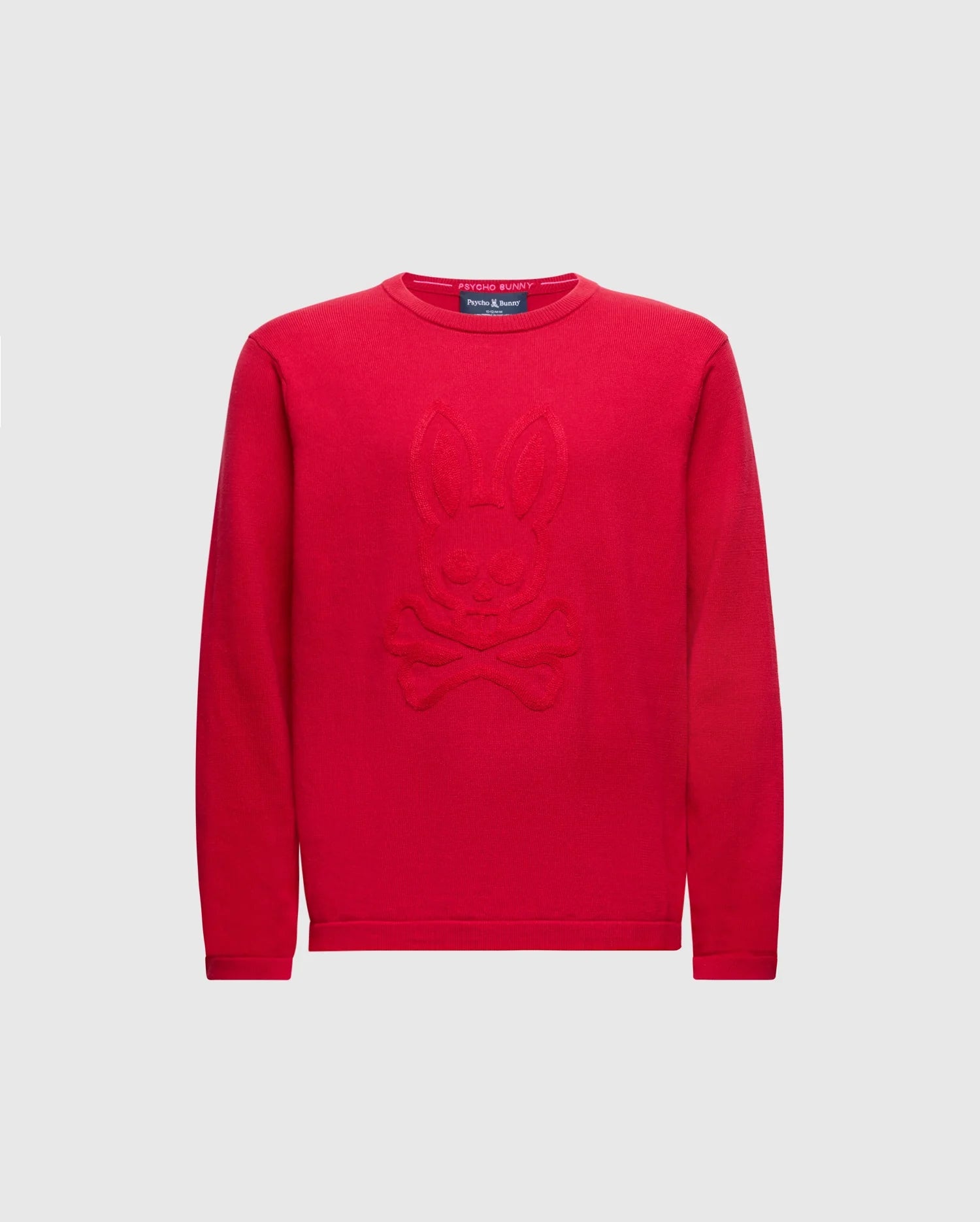 The KIDS COORY CHAINSTITCH COTTON SWEATER by Psycho Bunny features a vibrant design with a cartoon bunny and crossbones on fine cotton. It has long sleeves, a round neckline, and is set on a plain white background.