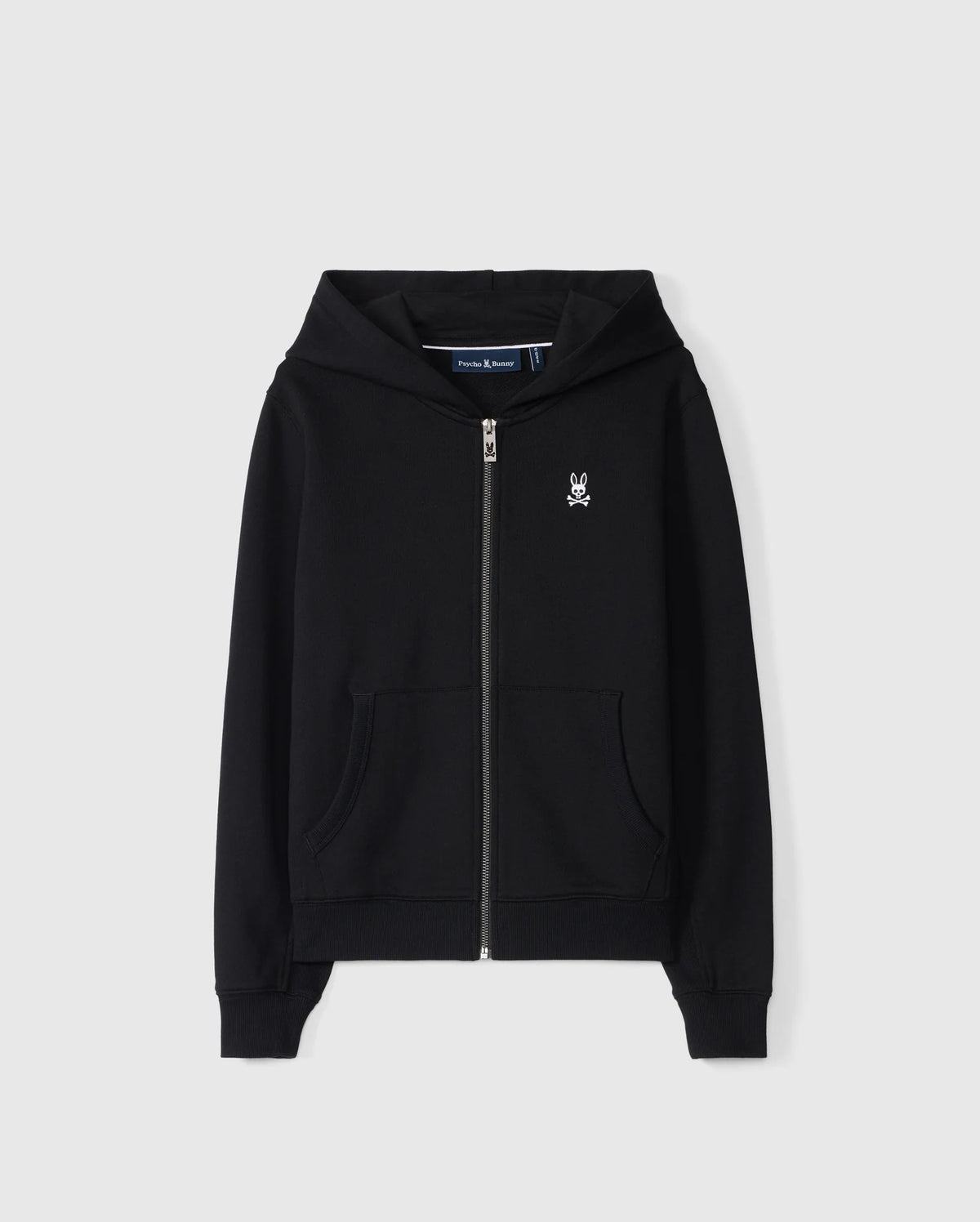 The KIDS LEVY ZIP FLEECE HOODIE - B0H720D200 by Psycho Bunny is a black French terry hoodie made from 100% cotton. It features a small white embroidered skull logo on the left chest, along with a front zipper and two pockets. The garment is showcased against a plain white background.
