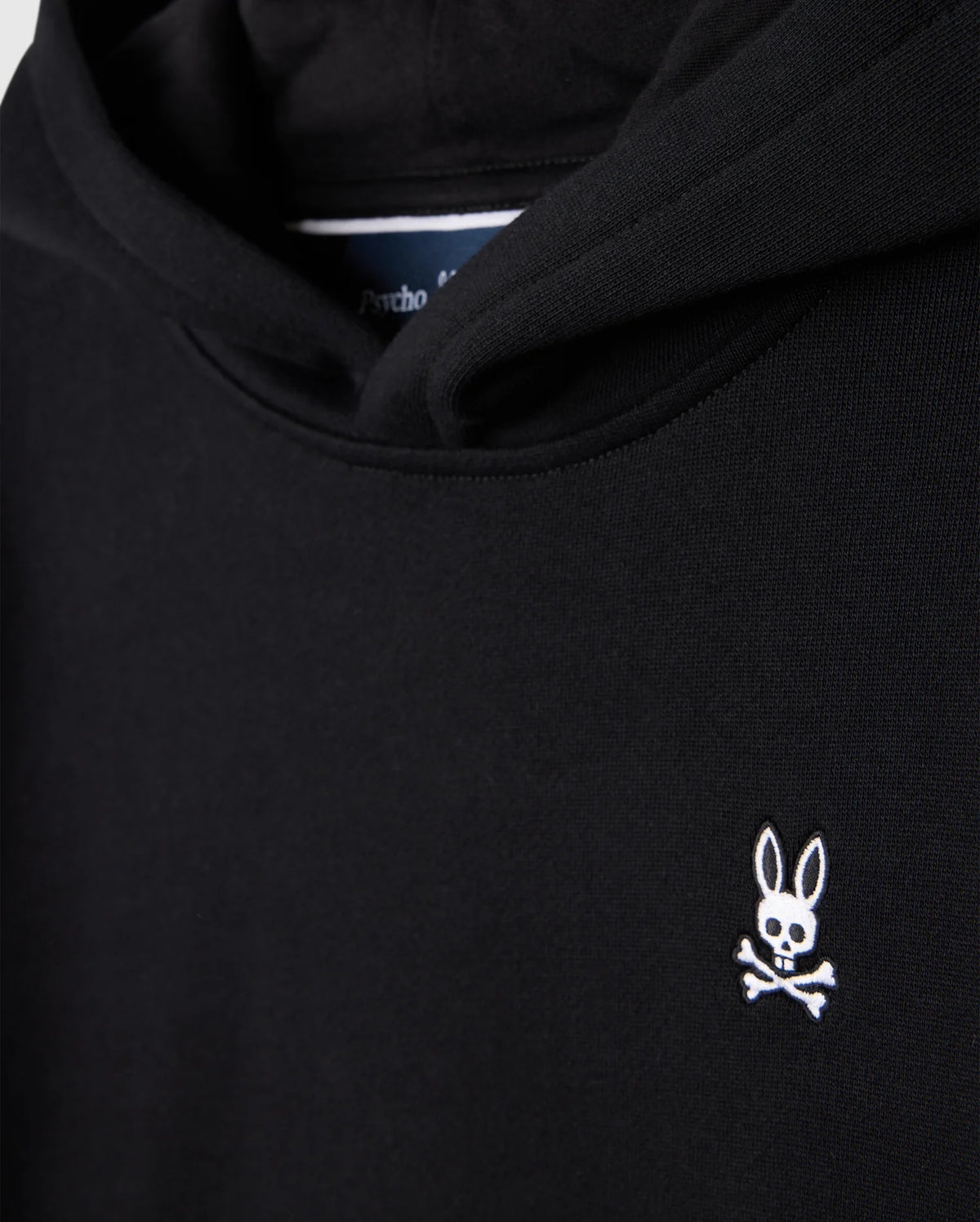 The KIDS LEVY FLEECE HOODIE - B0H859D200 by Psycho Bunny is crafted from 100% cotton and offers a regular fit. It boasts a black design accented by a small white logo on the chest, featuring a rabbit's head with crossed bones beneath it.