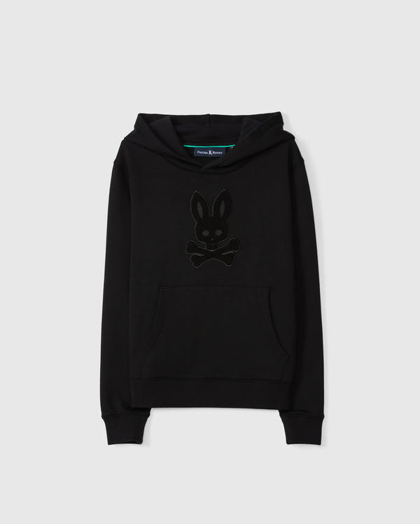Introducing the KIDS PACIFIC CHENILLE HOODIE - B0H930D200 by Psycho Bunny, a black pullover hoodie made from soft French terry. It features a front pocket and hood with a distinctive dark-toned logo design resembling a bunny head with crossbones underneath, stunningly contrasted against a plain white background.