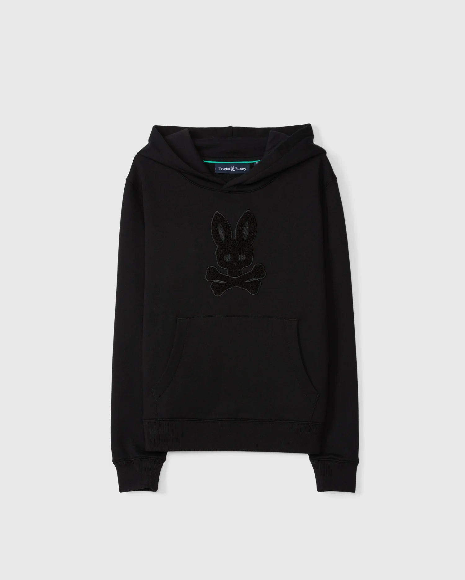 Introducing the KIDS PACIFIC CHENILLE HOODIE - B0H930D200 by Psycho Bunny, a black pullover hoodie made from soft French terry. It features a front pocket and hood with a distinctive dark-toned logo design resembling a bunny head with crossbones underneath, stunningly contrasted against a plain white background.