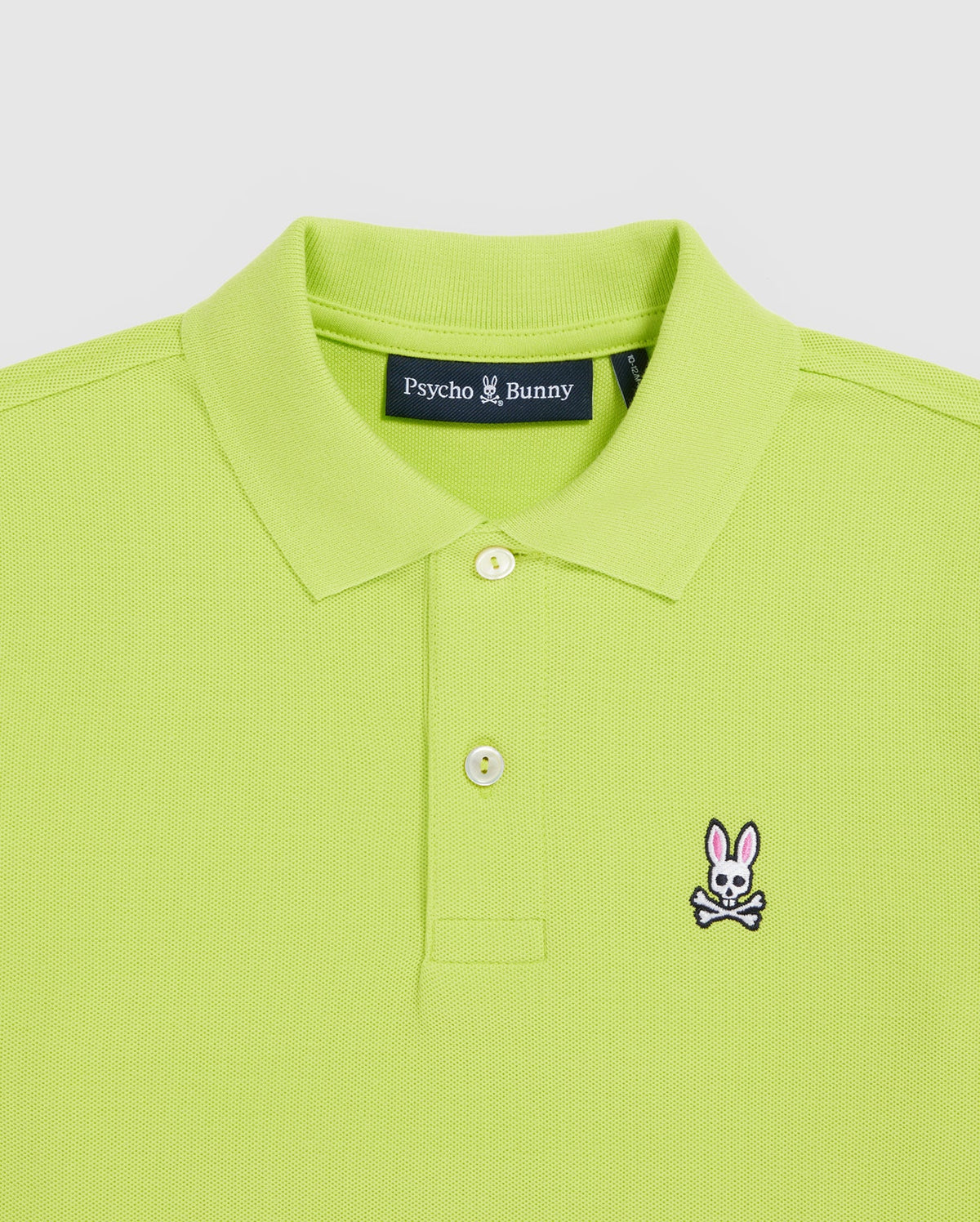 The Psycho Bunny Kids Classic Polo (B0K001CRPC) in lime green features a fold-over collar, two buttons, and a chest embroidery of a bunny with crossbones. Made from Pima cotton for quality, it offers a regular fit design.